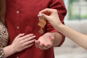real estate agent giving house key to couple, closeup