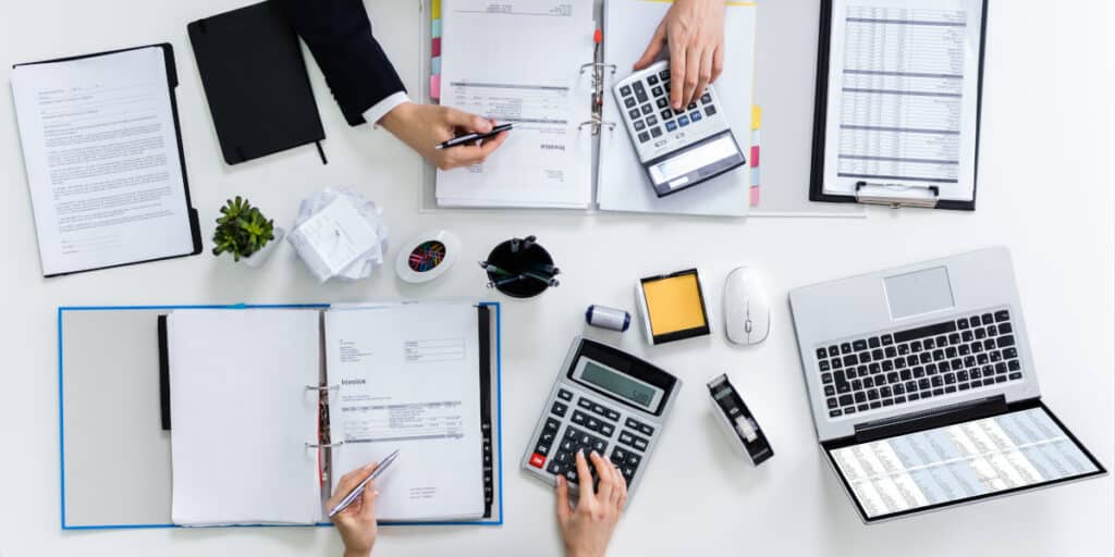 high,angle,view,of,two,businesspeople,calculating,bills,in,office
