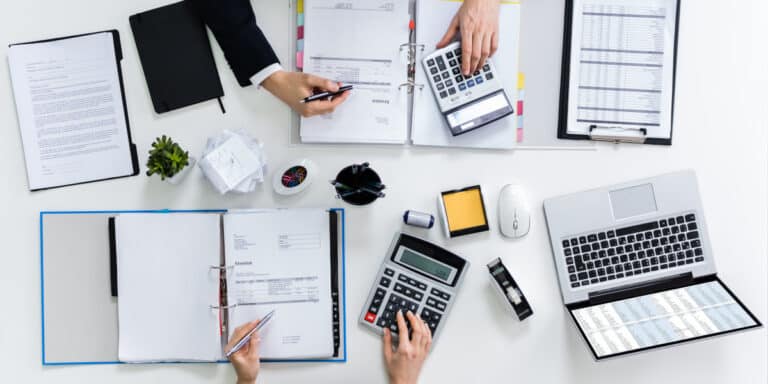 high,angle,view,of,two,businesspeople,calculating,bills,in,office