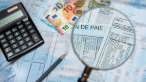 french payroll with a calculator, euro cash, and a magnifying glass