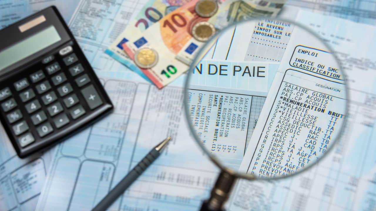 french payroll with a calculator, euro cash, and a magnifying glass